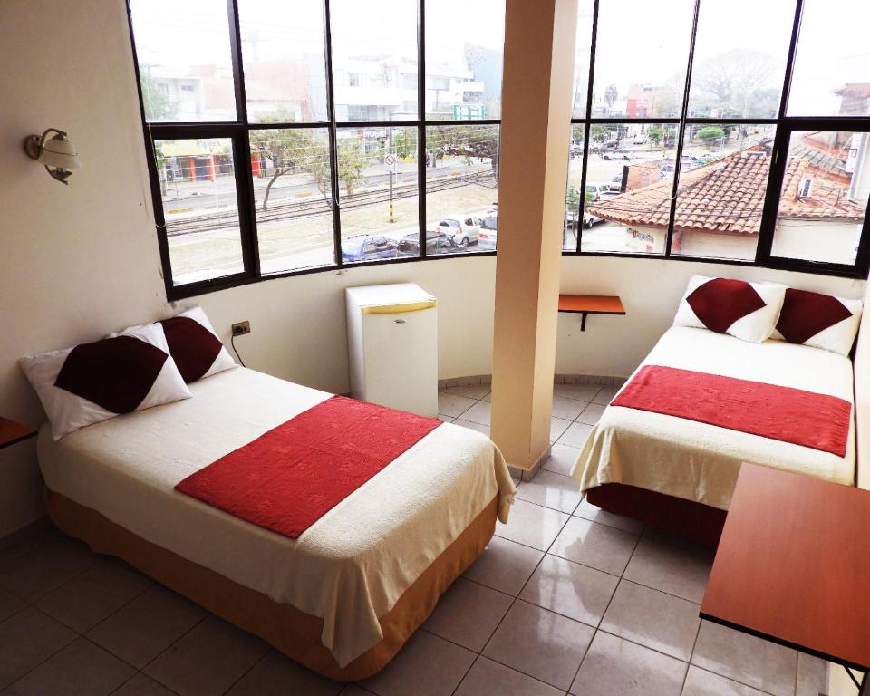 two beds in a room with large windows at Hotel Plaza Center in Santa Cruz de la Sierra