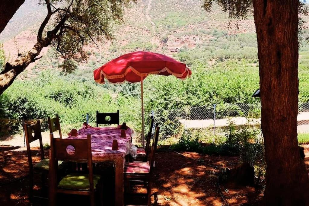 een tafel met een rode parasol en stoelen bij Découvrez les montagnes de l'Ourika, l'Atlas du Maro-c in Marrakesh