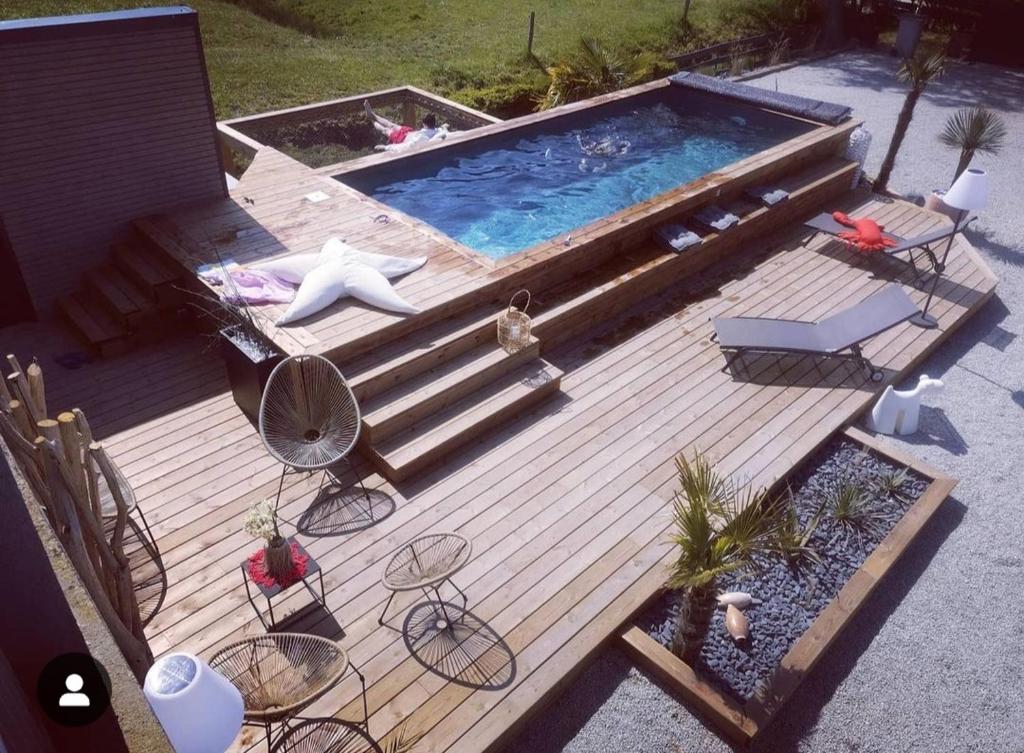 - une vue de tête sur une terrasse en bois avec une piscine dans l'établissement Woodland's House, à Hermanville-sur-Mer