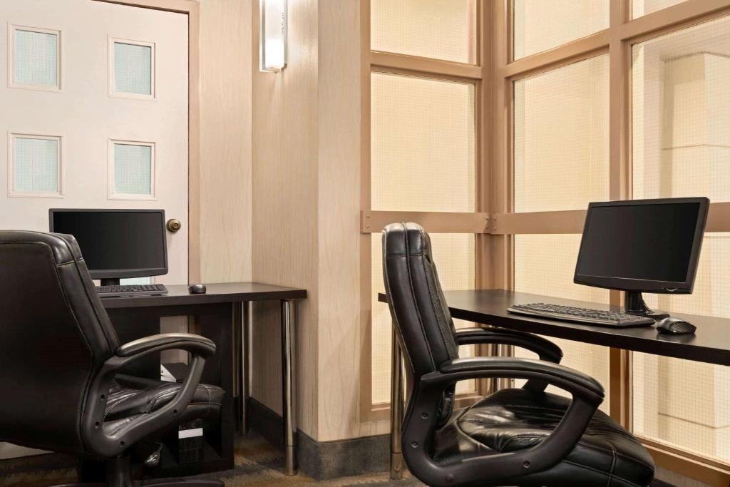 une chambre avec deux bureaux et deux écrans d'ordinateur dans l'établissement Travelodge by Wyndham Oshawa Whitby, à Oshawa