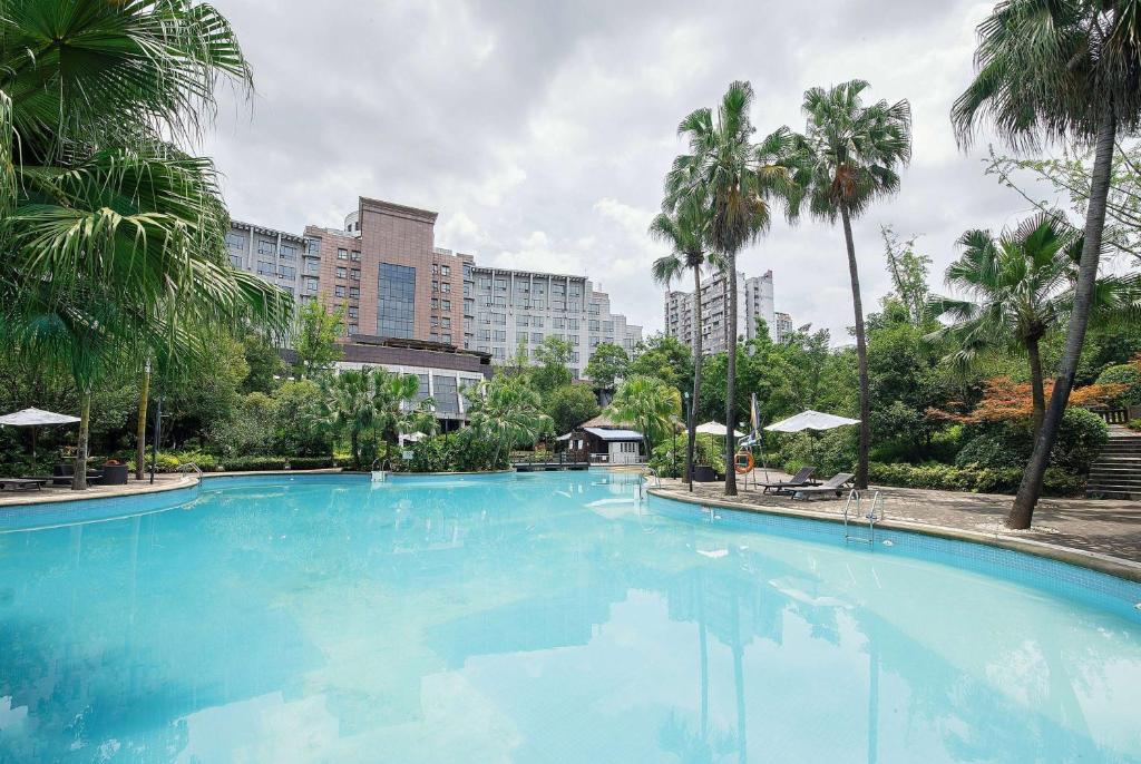 duży basen z palmami i budynkami w obiekcie Ramada Plaza by Wyndham Chongqing West w mieście Dazu