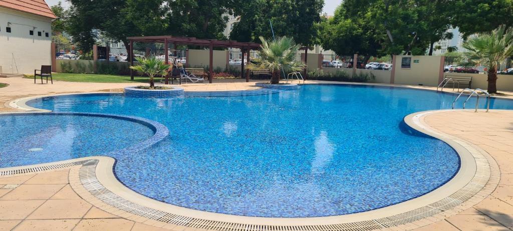 a large swimming pool with blue water at Near metro, spacious apartment has 1 bedroom, living room, kitchen, 2 bathrooms, storage room, balcony, outside you will have temperature controlled pools, gardens and free parking in Dubai