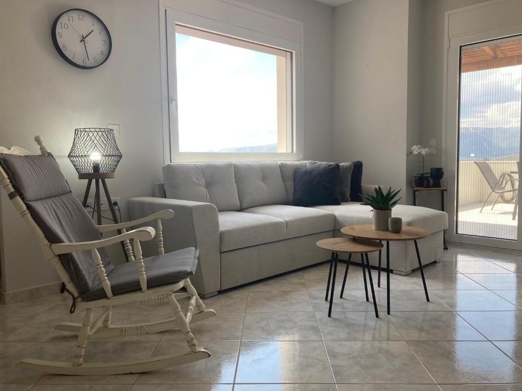 ein Wohnzimmer mit einem Sofa, einem Stuhl und einer Uhr in der Unterkunft Enchanting Mycenae - Your Greek holiday retreat in Argos