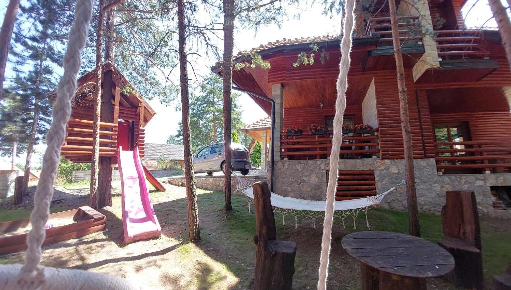 a log cabin with a swing in the yard at Vila MINA in Bajina Bašta