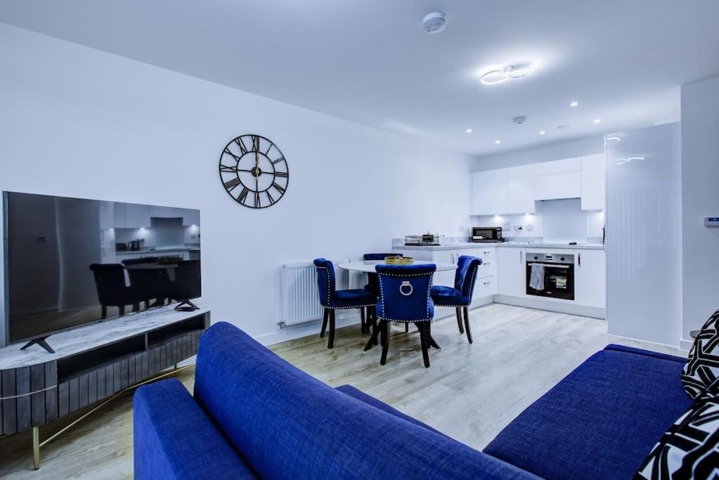a living room with a blue couch and a kitchen at Brand New apartment next to Lakeside Shopping mall, Essex in West Thurrock