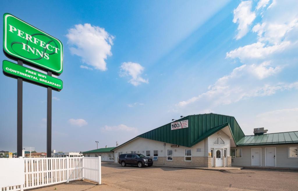 a green sign in front of a building at Perfect Inns & Suites in Weyburn