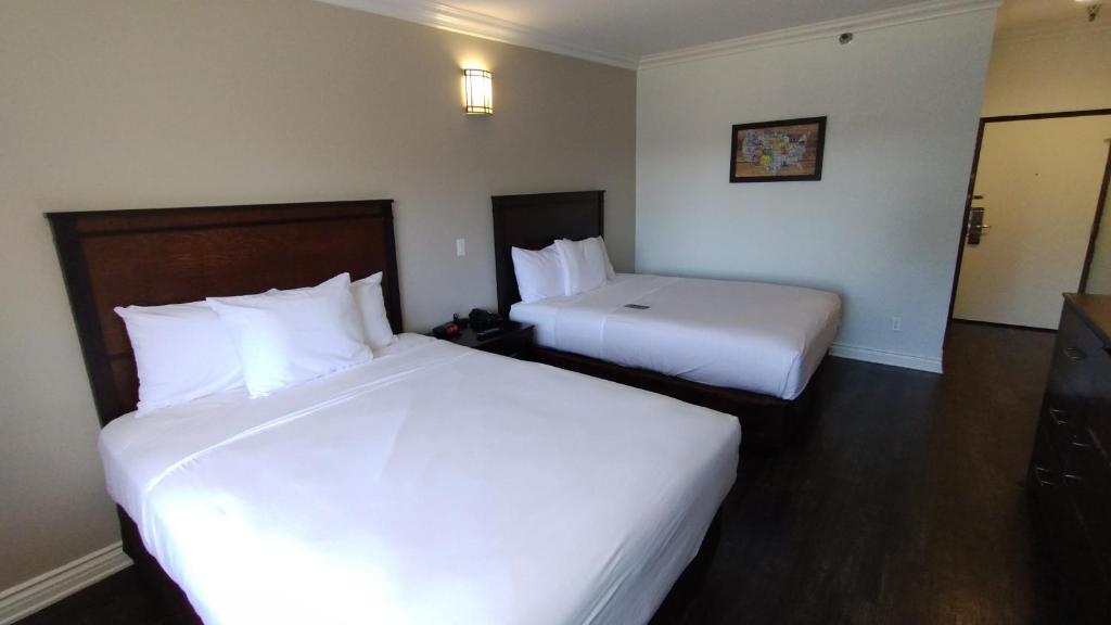 um quarto de hotel com duas camas com lençóis brancos em Baymont by Wyndham Ontario em Ontario
