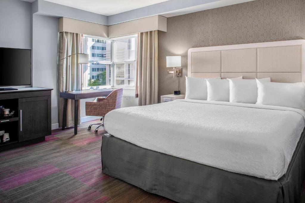 a hotel room with a large bed and a desk at Hampton Inn Miami Beach - Mid Beach in Miami Beach