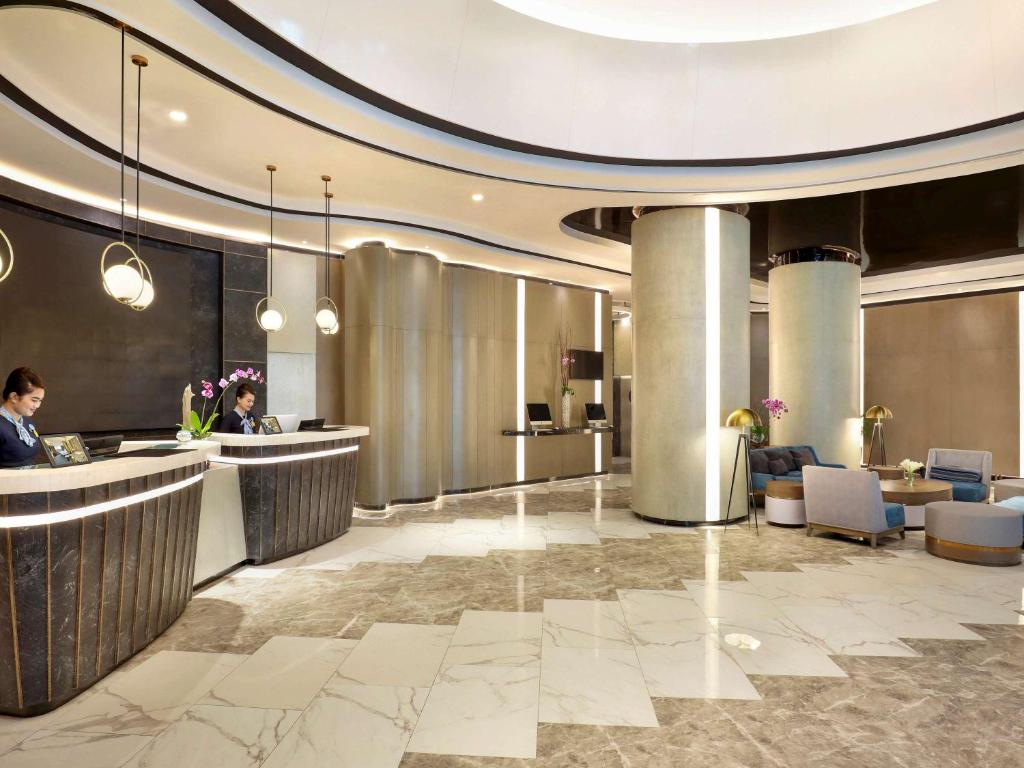 a lobby of a hotel with people sitting at a counter at Novotel Suites Yogyakarta Malioboro in Yogyakarta