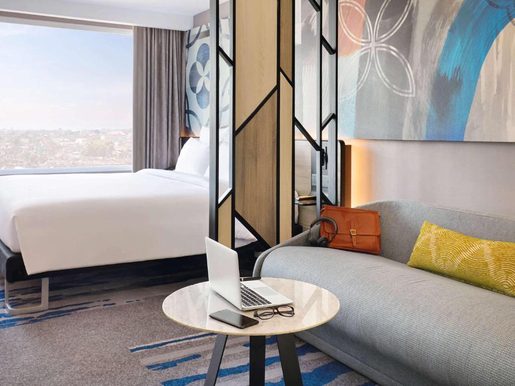 a hotel room with a couch and a laptop on a table at Novotel Suites Yogyakarta Malioboro in Yogyakarta