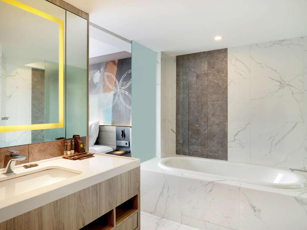a bathroom with a white tub and a sink at Novotel Suites Yogyakarta Malioboro in Yogyakarta
