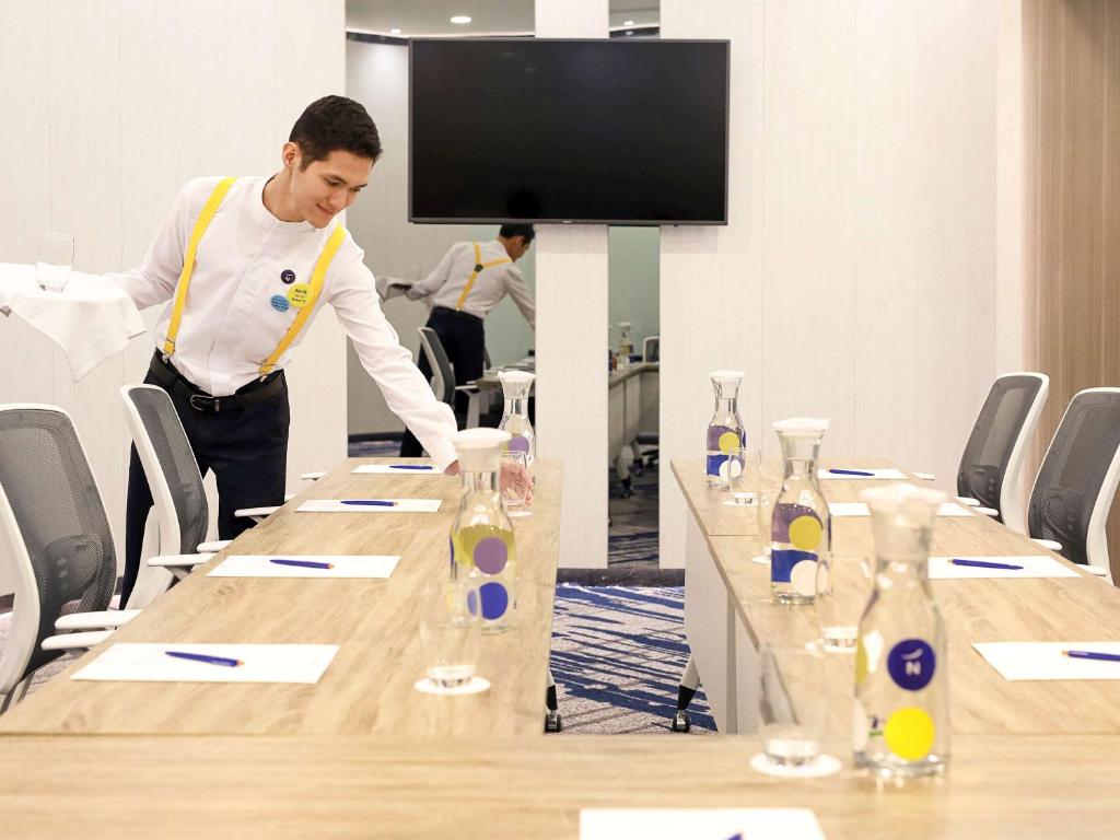 a man standing at a table in a conference room at Novotel Suites Yogyakarta Malioboro in Yogyakarta