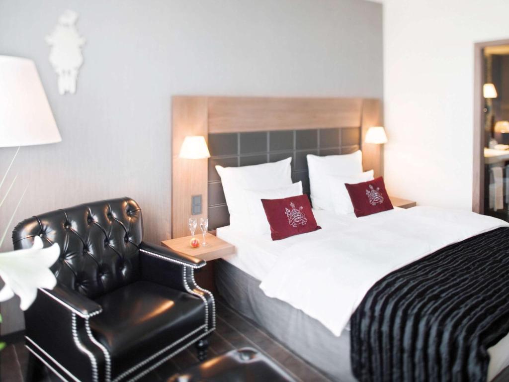 a hotel room with a bed and a chair at Mövenpick Hotel Stuttgart Airport in Stuttgart