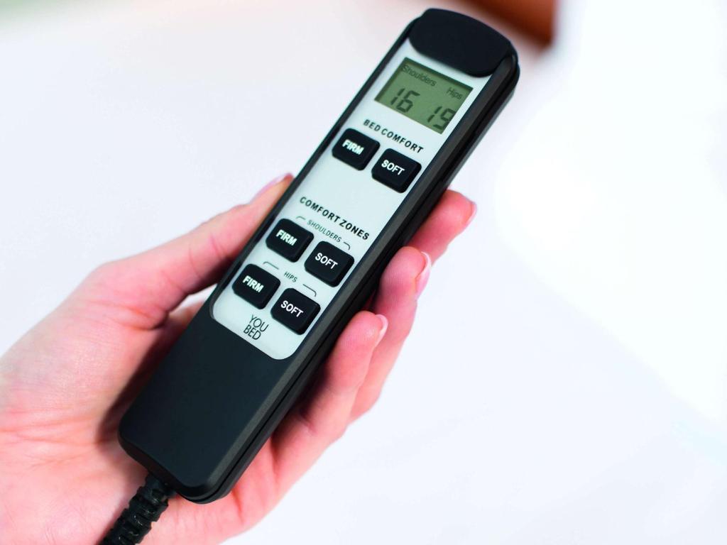 a person holding a remote control in their hand at Mövenpick Hotel Stuttgart Airport in Stuttgart
