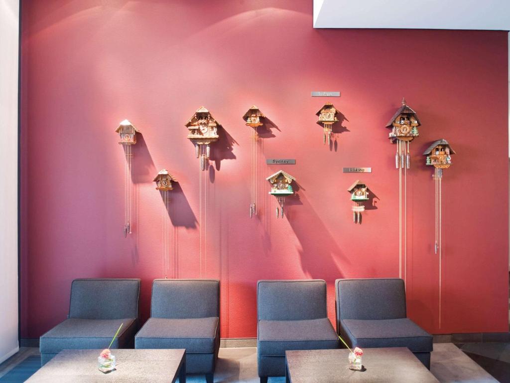 a wall with a bunch of chairs and clocks at Mövenpick Hotel Stuttgart Airport in Stuttgart