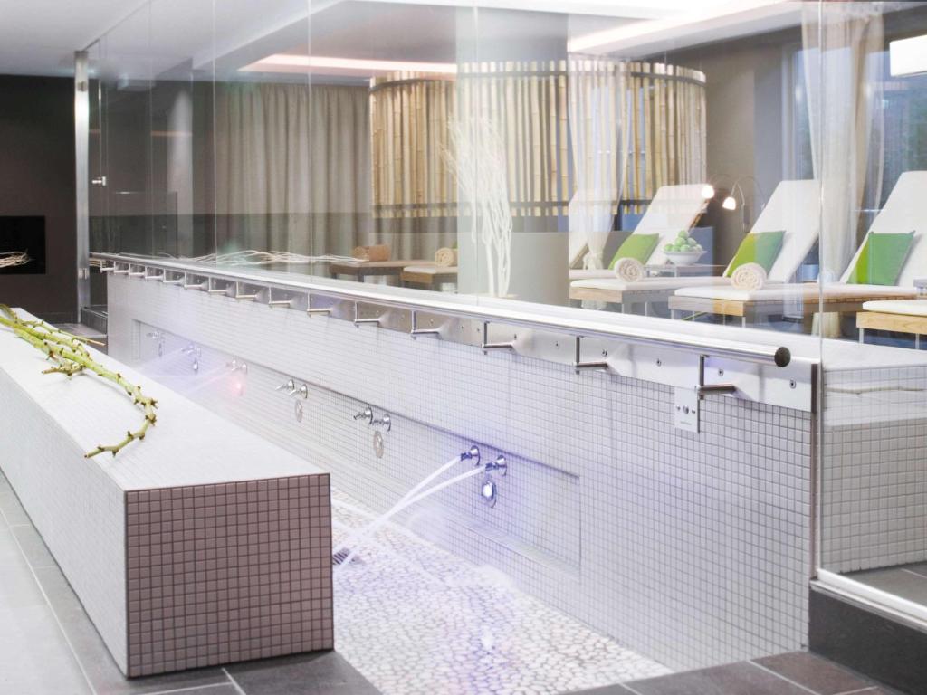 a bathroom with a tub and a shower with sinks at Mövenpick Hotel Stuttgart Airport in Stuttgart