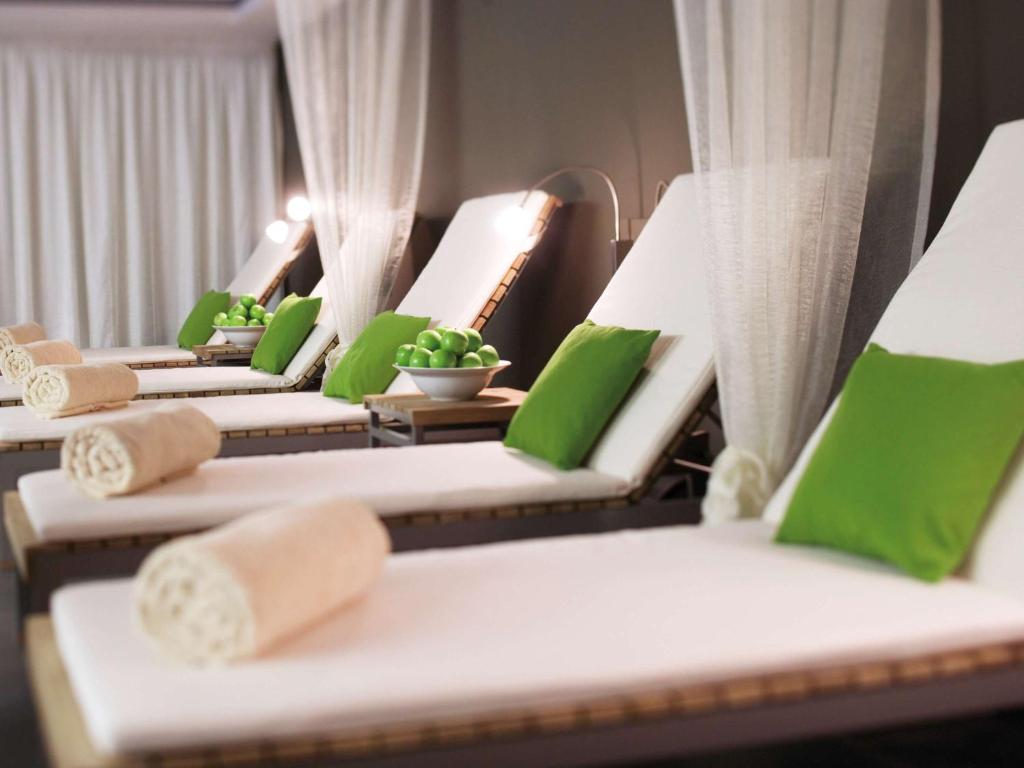 a row of lounge chairs with green pillows at Mövenpick Hotel Stuttgart Airport in Stuttgart