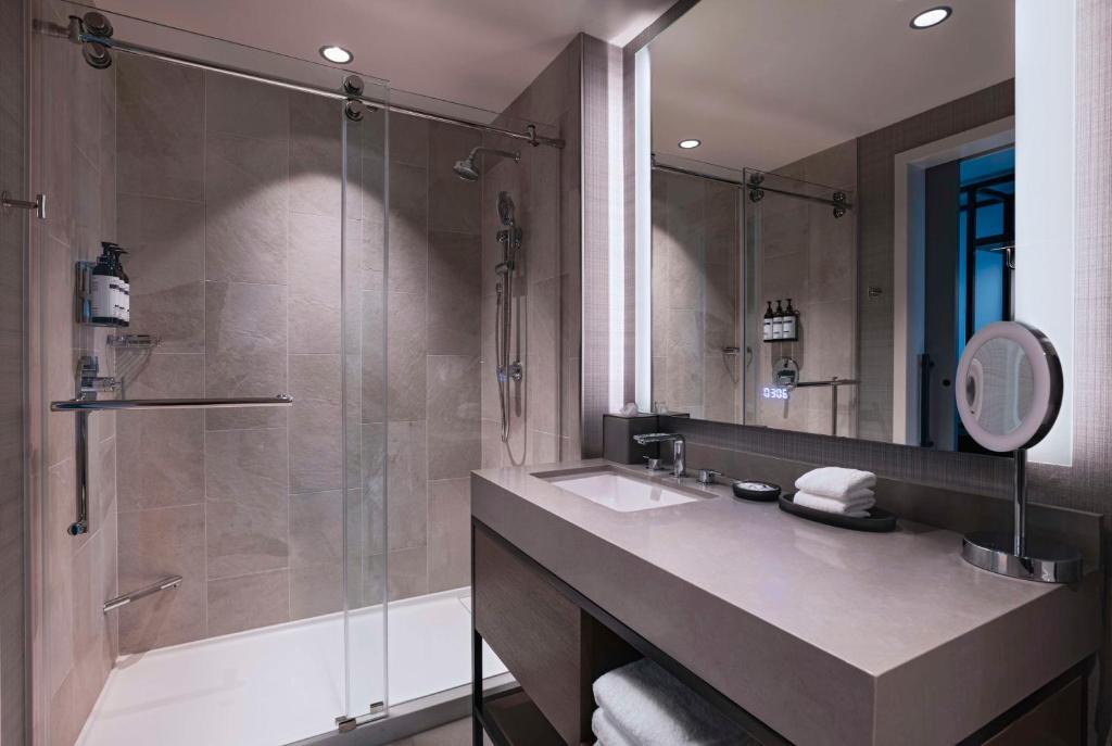 貝敦的住宿－Hyatt Regency Baytown-Houston，浴室配有盥洗盆和带镜子的淋浴
