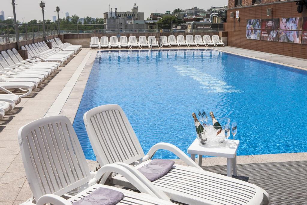 首爾的住宿－哈密​​爾頓酒店，一个带椅子和桌子的游泳池,上面有花瓶