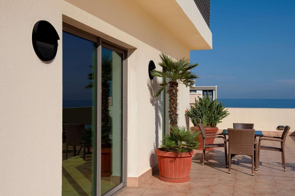 une terrasse avec une table et des chaises et l'océan dans l'établissement Radisson Blu Martinez Beirut, à Beyrouth