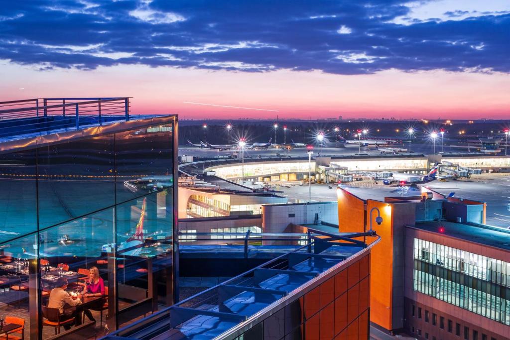 people sitting at tables on the balcony of a building at Radisson Blu Hotel Moscow Sheremetyevo Airport in Khimki