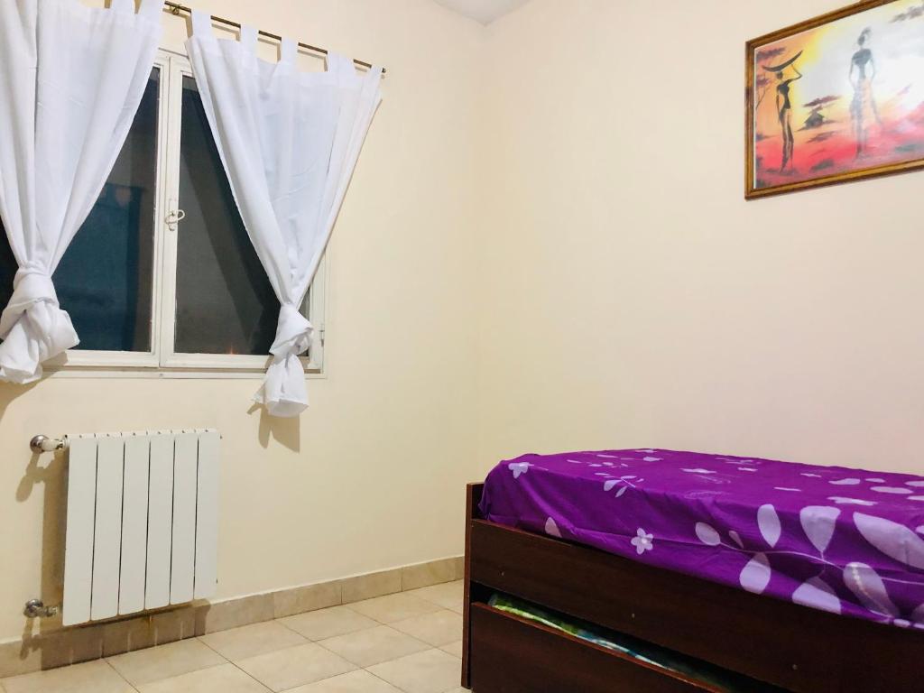 una camera da letto con un letto con lenzuola viola e una finestra di Anita depto Jujuy a San Salvador de Jujuy