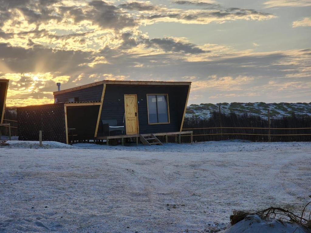 een klein huis in de sneeuw met de zonsondergang op de achtergrond bij Refugios del Mar in Punta de Choros