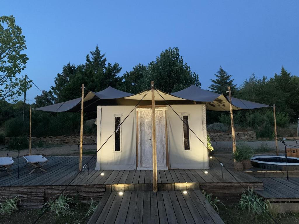 - une tente blanche sur une terrasse en bois la nuit dans l'établissement Lodge Luxe et insolite spirit of Bali - La Noccemada, à Saint-Julien