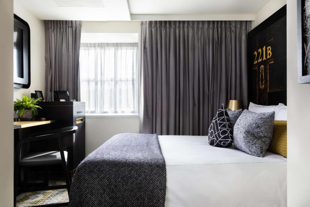 a hotel room with a bed and a desk at Holmes Hotel London in London