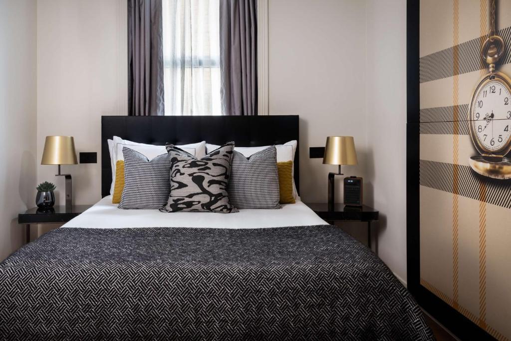 a bedroom with a bed with pillows and a clock at Holmes Hotel London in London