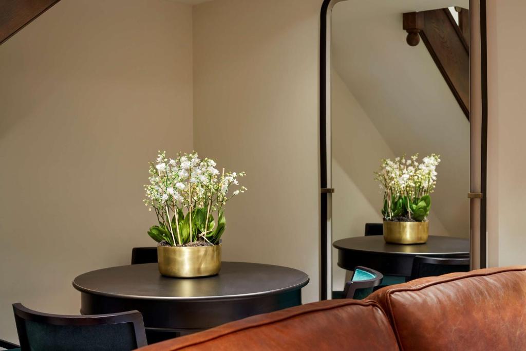 a living room with two tables with flowers on them at Holmes Hotel London in London