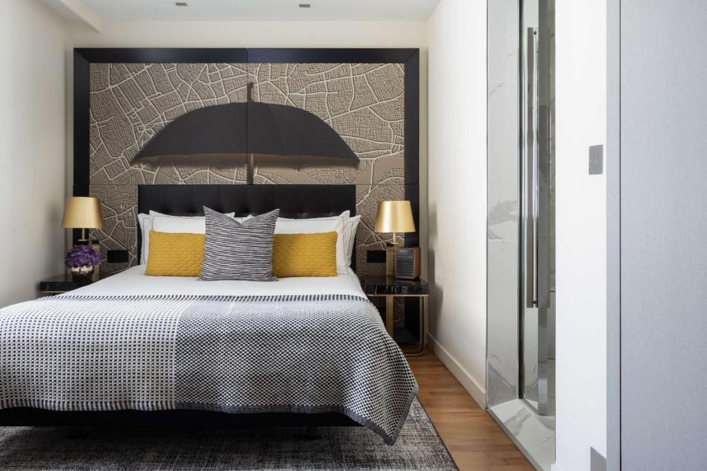 a bedroom with a bed with a black headboard and yellow pillows at Holmes Hotel London in London
