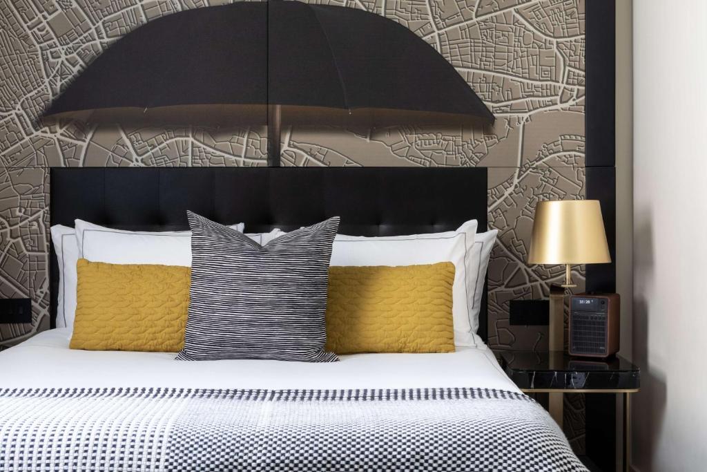 a bedroom with a bed with a black headboard and yellow pillows at Holmes Hotel London in London