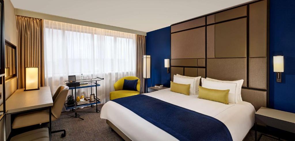 ユトレヒトにあるパーク プラザ ユトレヒトの大きなベッドとデスクが備わるホテルルームです。