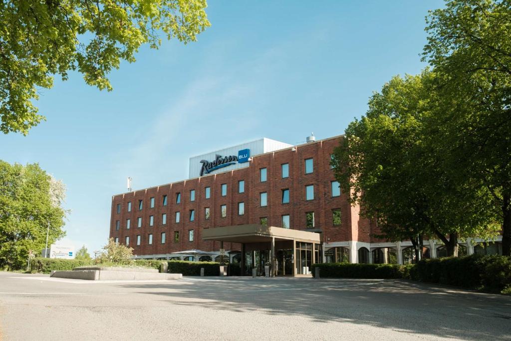 ein großes rotes Backsteingebäude vor einer Straße in der Unterkunft Radisson Blu Arlandia Hotel, Stockholm-Arlanda in Arlanda