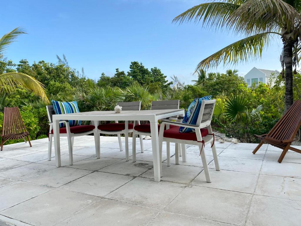 a white table and chairs on a patio with palm trees at SeaSide Townhome, Spacious 2br 3bath Leeward Grace Bay, Providenciales, walk to beach in Providenciales
