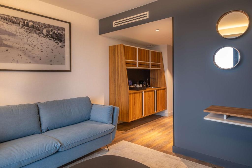 a living room with a blue couch and a table at Radisson Blu Grand Hotel & Spa, Malo-Les-Bains in Dunkerque