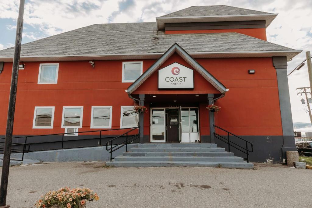 un edificio rojo con un cartel de invitado en él en Coast Fort St John Hotel, en Fort Saint John