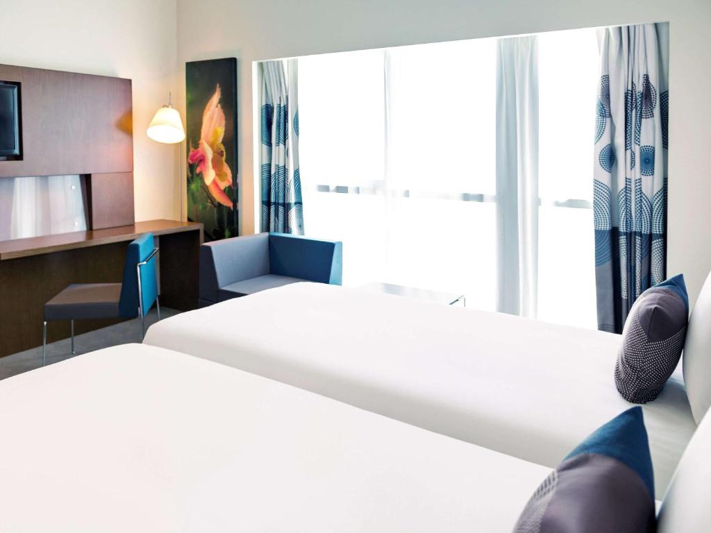 a hotel room with two beds and a tv at Novotel Fujairah in Fujairah