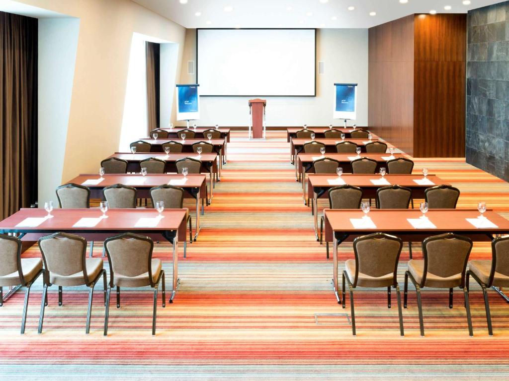 a lecture hall with tables and chairs and a podium at Novotel Fujairah in Fujairah