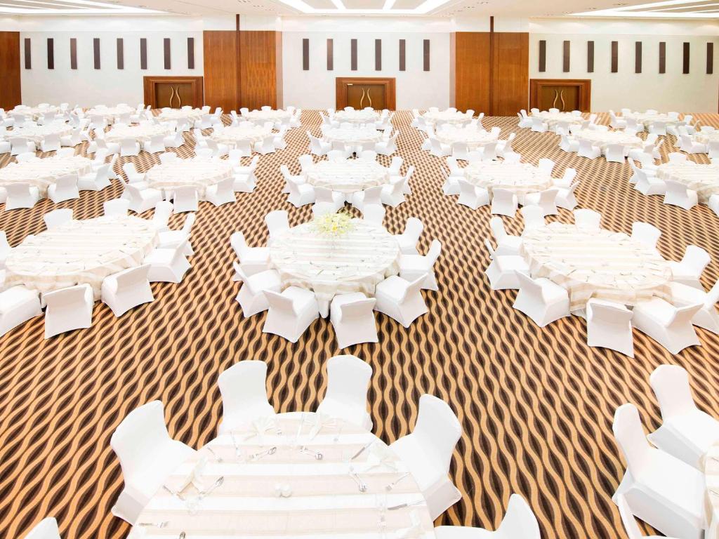 a large banquet hall with white tables and white chairs at Novotel Fujairah in Fujairah