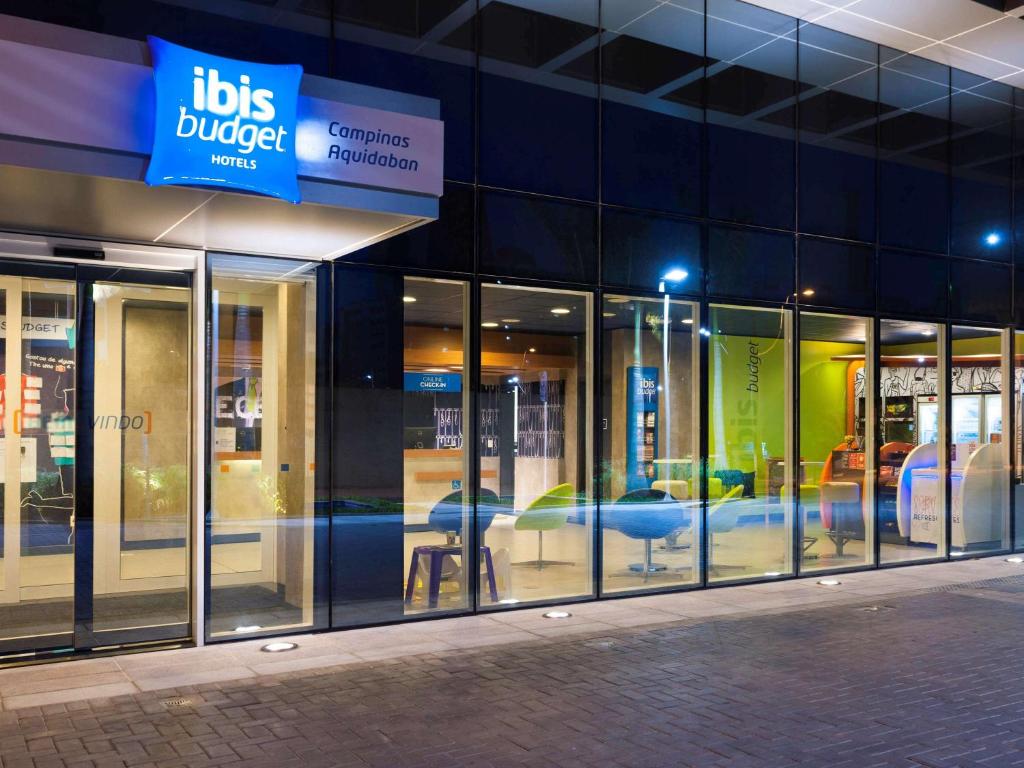 a building with a bunch of glass doors and tables at ibis budget Campinas Aquidaban in Campinas