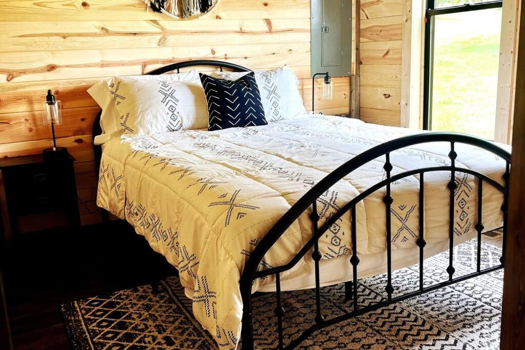 a bed in a room with a wooden wall at #4 Kentucky Bourbon Trail Bourbon Barrel Cottages in Lawrenceburg