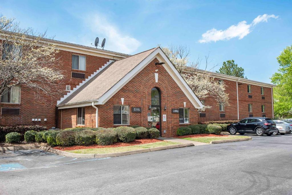 a brick building with a car parked in front of it at Suburban Studios Montgomery East I-85 in Montgomery