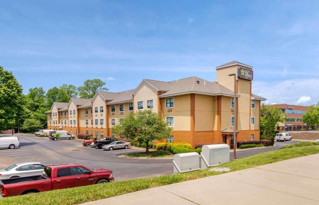 un gran edificio con coches estacionados en un estacionamiento en Extended Stay America Suites - Charlotte - University Place en Charlotte