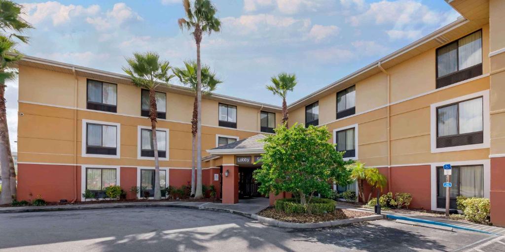 a large building with palm trees in front of it at Extended Stay America Suites - Orlando - Orlando Theme Parks - Vineland Rd in Orlando