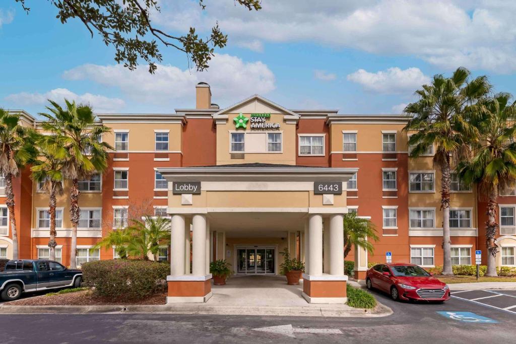 um grande edifício laranja com palmeiras em frente em Extended Stay America Suites - Orlando - Convention Center - 6443 Westwood em Orlando