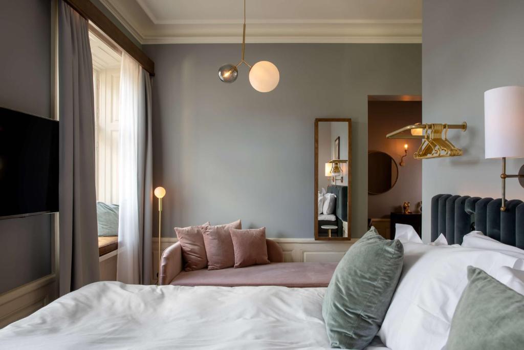 a bedroom with a bed and a chair and a mirror at Hotel Frantz, WorldHotels Crafted in Stockholm