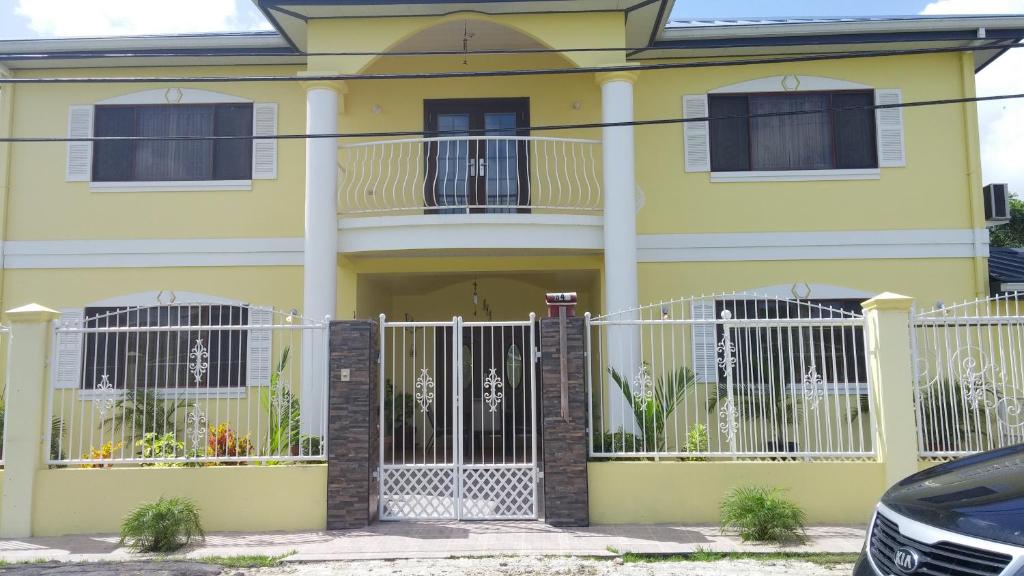 a yellow house with a white fence in front of it at The Green Palms Getaway, Palmiste, San Fernando - 6 BR 4 Bath 12 guests 