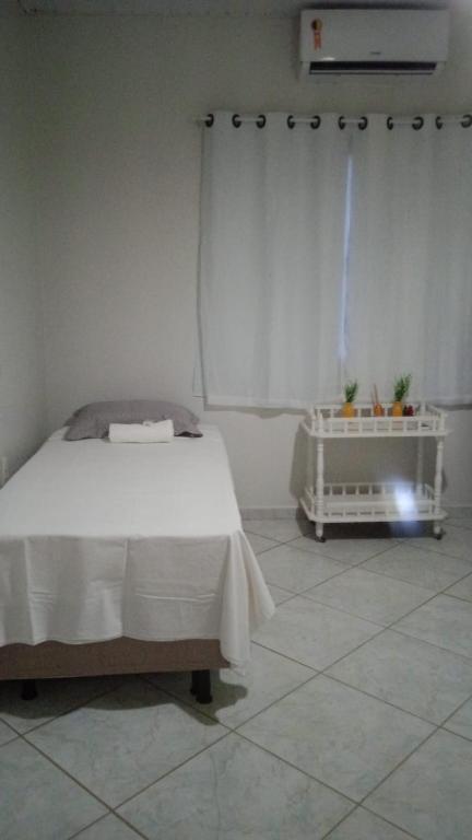 a white bedroom with a bed and a window at Pousada Balsas in Balsas